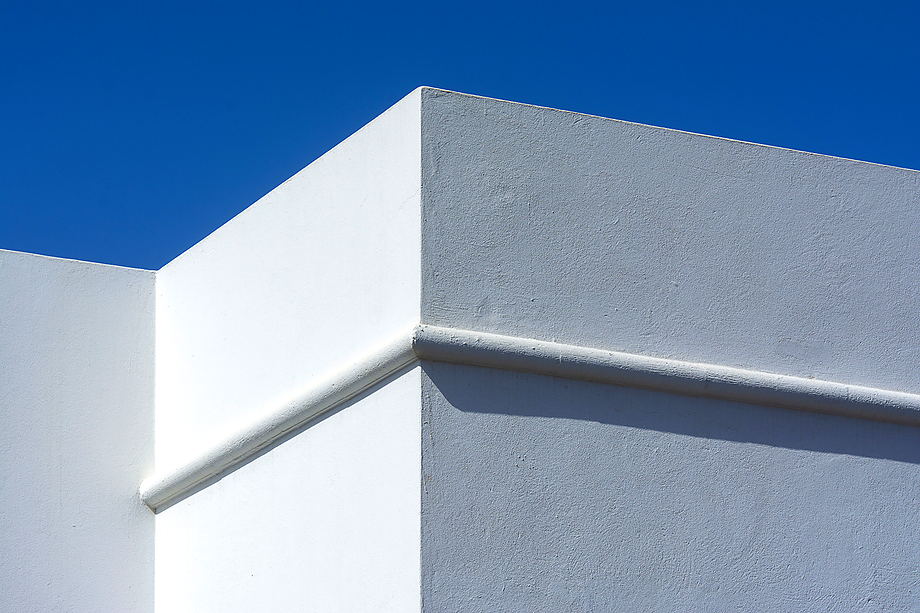 Strakke witte gevel in buitenstucwerk tegen een blauwe lucht